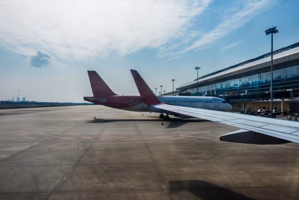 Route hacking dan tiket open-jaw: dua pesawat penumpang terparkir di apron dekat terminal kaca modern