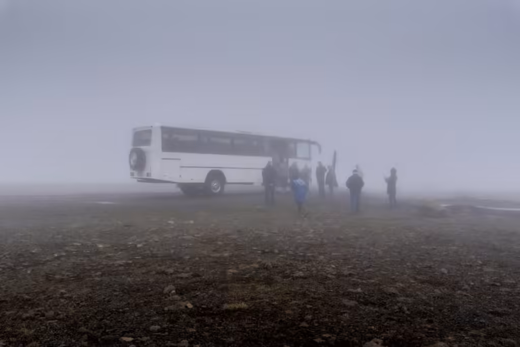 Mid-range tour operators: a small group gathered beside its coach on a foggy plateau