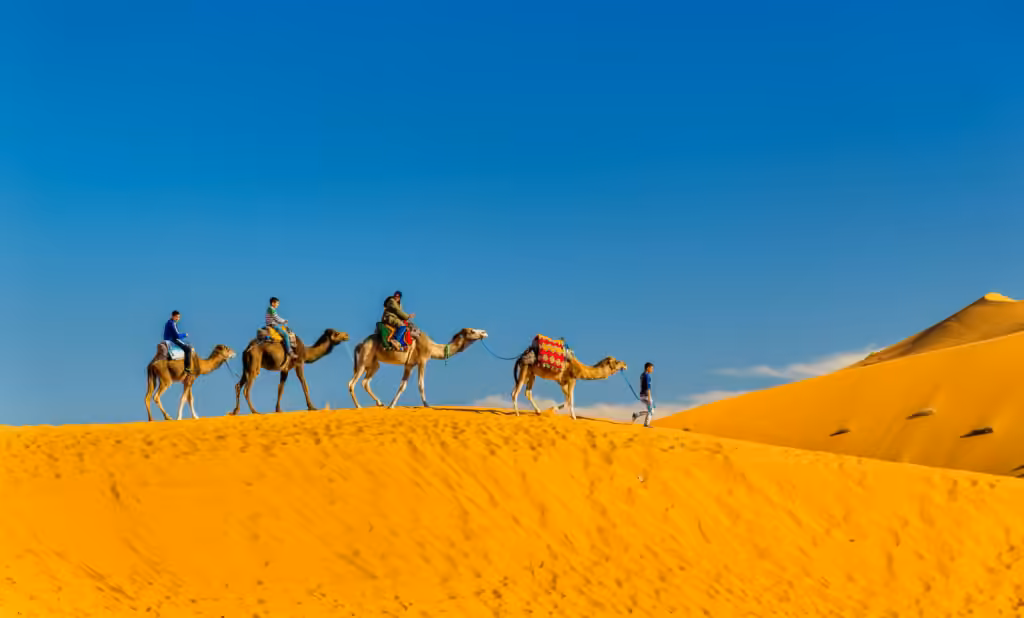 Escursione in cammello vicino a Merzouga: turisti in sella lungo il crinale di una duna dell'Erg Chebbi