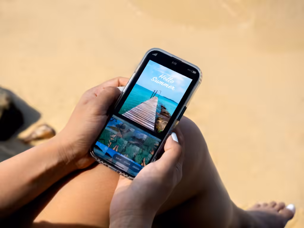 Lightroom Mobile czy Darkroom: smartfon trzymany nad piaskiem, na ekranie obróbka zdjęcia z plaży